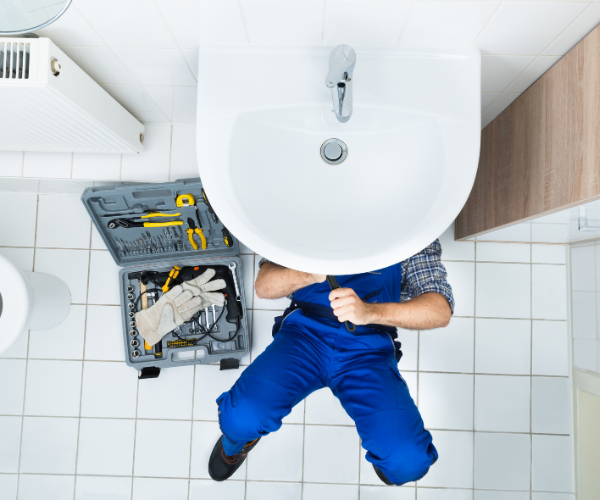 plumber working on the pipes under a sink